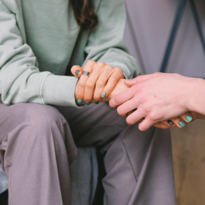 Two people holding hands in a supportive way